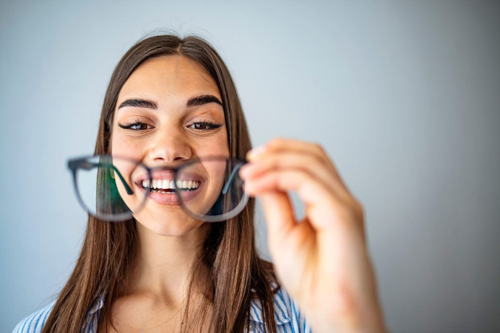 happy young lady looking at her new glasses